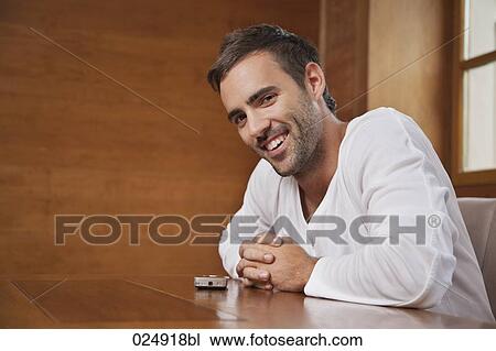 portrait of young man sitting at table with mobile phone View Large Photo Image Stock Image - portrait of young man sitting at table with mobile phone. Fotosearch