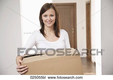 Stock Image - portrait of young woman carrying moving box. Fotosearch