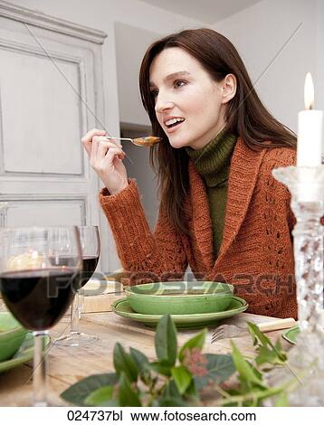 Stock Image - portrait of young woman eating soup. Fotosearch
