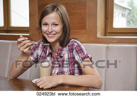 Stock Image - portrait of young woman having glass of latte. Fotosearch
