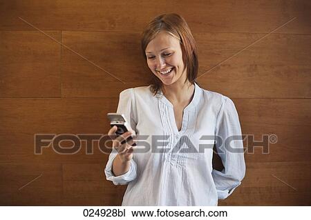 Stock Image - portrait of young woman looking at display of mobile phone. Fotosearch