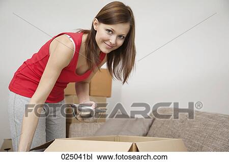 Stock Image - portrait of young woman packing to move home. Fotosearch