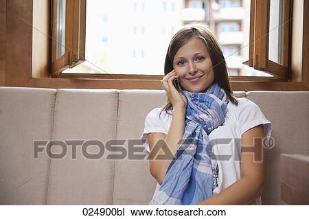 portrait of young woman sitting by window talking on mobile phone View Large Photo Image Stock Image - portrait of young woman sitting by window talking on mobile phone. Fotosearch