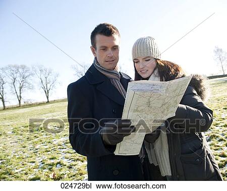 Stock Image - young couple having a walk in winter looking at map. Fotosearch