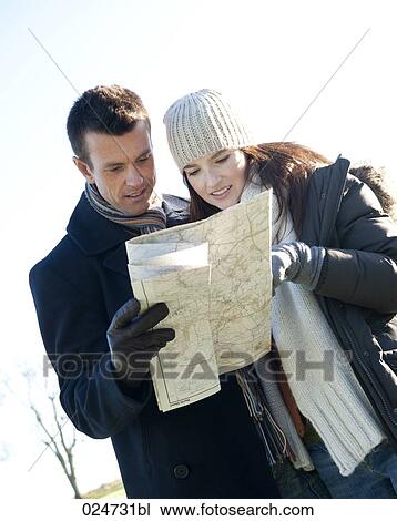 Stock Image - young couple having a walk in winter looking at map. Fotosearch