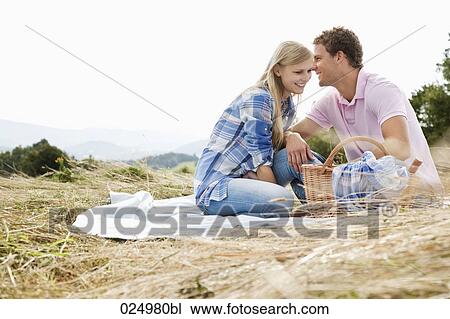Stock Image - young couple having picnic in field. Fotosearch