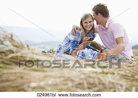 Stock Image - young couple having picnic in field. Fotosearch