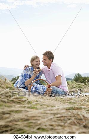 Stock Image - young couple having picnic in field. Fotosearch