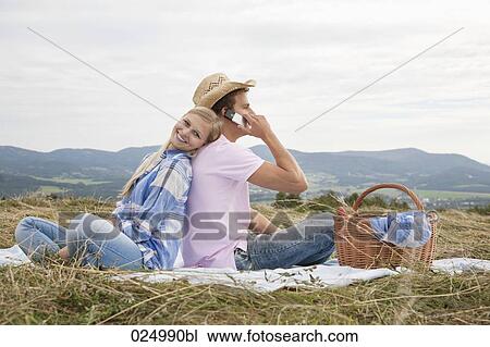 Stock Image - young couple having picnic in field. Fotosearch