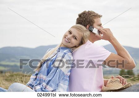 Stock Image - young couple having picnic in field. Fotosearch