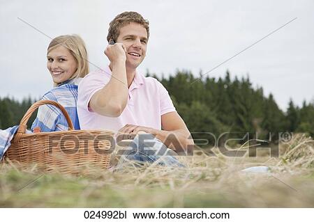 Stock Image - young couple having picnic in field. Fotosearch