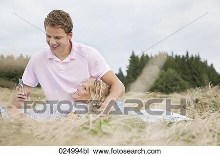 young couple in field man looking at display of mobile phone View Large Photo Image Stock Image - young couple in field man looking at display of mobile phone. Fotosearch