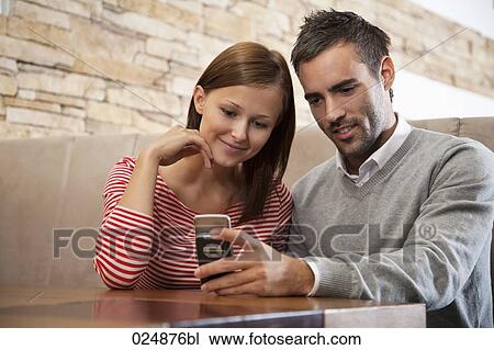 Stock Image - young couple looking at display of mobile phone. Fotosearch