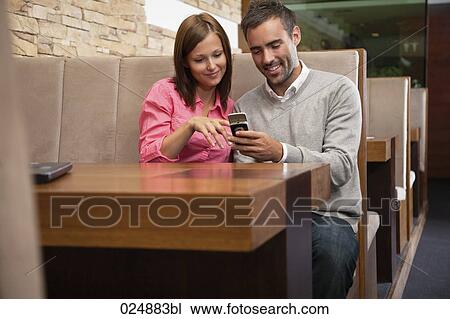 young couple looking at display of mobile phone at restaurant View Large Photo Image Stock Image - young couple looking at display of mobile phone at restaurant. Fotosearch