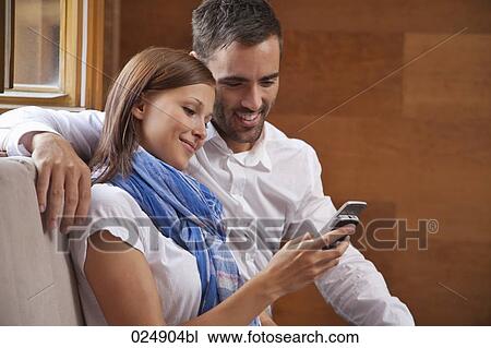 Stock Image - young couple looking at display of mobile phone. Fotosearch