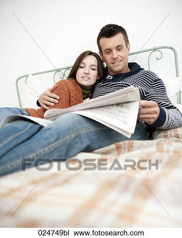 young couple lying bed together man reading magazine View Large Photo Image Stock Image - young couple lying bed together man reading magazine. Fotosearch