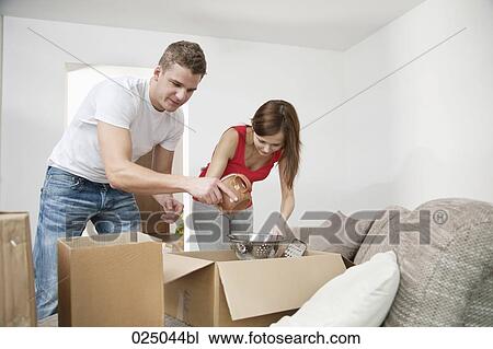 Stock Image - young couple packing crockery in cardboard boxes. Fotosearch