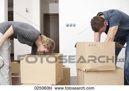 Stock Image - young couple searching for something in moving boxes. Fotosearch