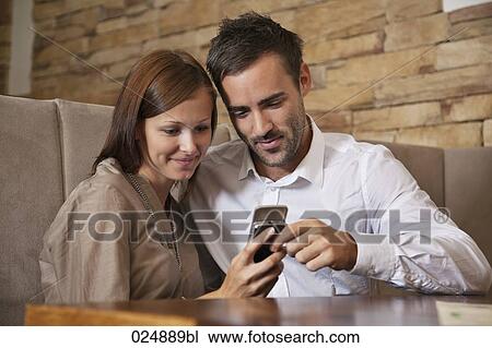 young couple sharing message on mobile phone at restaurant View Large Photo Image Stock Image - young couple sharing message on mobile phone at restaurant. Fotosearch