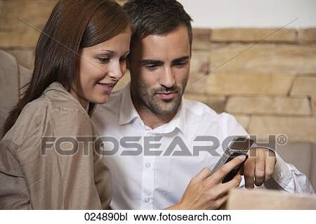 young couple sharing message on mobile phone at restaurant View Large Photo Image Stock Image - young couple sharing message on mobile phone at restaurant. Fotosearch