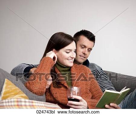 young couple sitting on sofa reading book View Large Photo Image Stock Image - young couple sitting on sofa reading book. Fotosearch