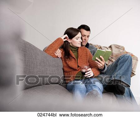 young couple sitting on sofa reading book View Large Photo Image Stock Image - young couple sitting on sofa reading book. Fotosearch