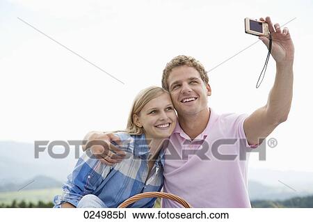 Stock Image - young couple taking picture of themselves with digital camera. Fotosearch