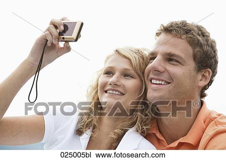 Stock Image - young couple taking self-portrait with digital camera. Fotosearch