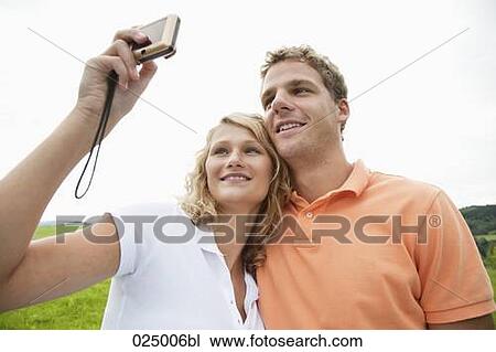 Stock Image - young couple taking self-portrait with digital camera. Fotosearch