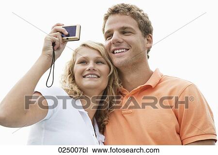 Stock Image - young couple taking self-portrait with digital camera. Fotosearch