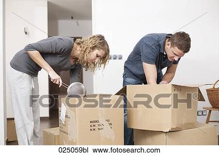 Stock Image - young couple unpacking moving boxes in new home. Fotosearch
