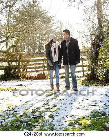 Stock Image - young couple walking through garden in winter. Fotosearch
