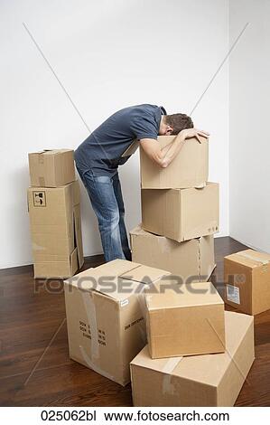 Stock Image - young man searching for something in moving boxes. Fotosearch