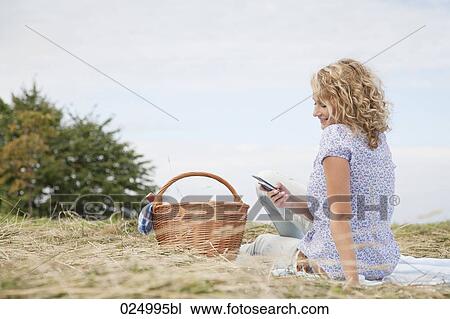 young woman having picnic reading text message on mobile phone View Large Photo Image Stock Image - young woman having picnic reading text message on mobile phone. Fotosearch