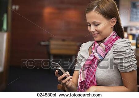Stock Image - young woman looking at display of her mobile phone. Fotosearch