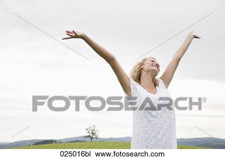 young woman on meadow raising her arms in the air View Large Photo Image Stock Image - young woman on meadow raising her arms in the air. Fotosearch