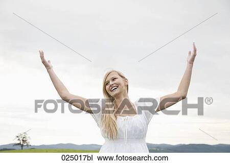 young woman on meadow raising her arms in the air View Large Photo Image Stock Image - young woman on meadow raising her arms in the air. Fotosearch