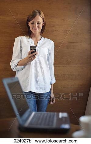 Stock Image - young woman reading message on mobile phone. Fotosearch