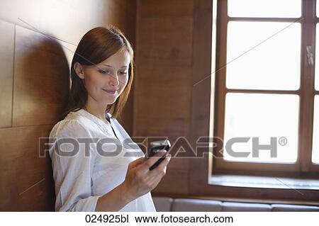 Stock Image - young woman reading on message on mobile phone. Fotosearch