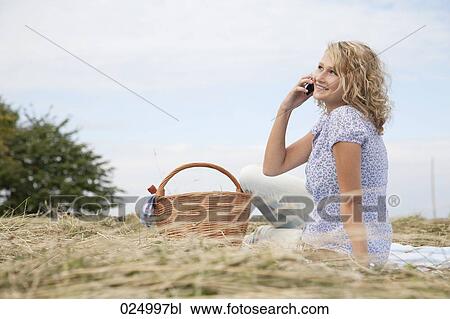 Stock Image - young woman talking on mobile phone in field. Fotosearch