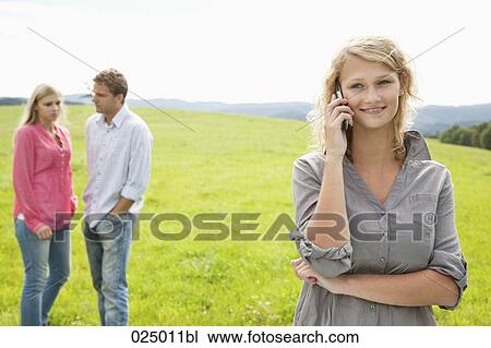 young woman talking on mobile phone on meadow View Large Photo Image Stock Image - young woman talking on mobile phone on meadow. Fotosearch