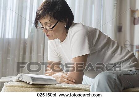 Stock Image - mature woman reading at home. Fotosearch