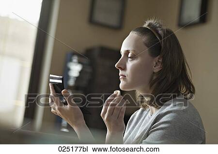 Stock Image - portrait of young woman applying make-up. Fotosearch