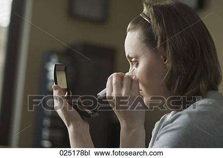 Stock Image - portrait of young woman applying make-up. Fotosearch