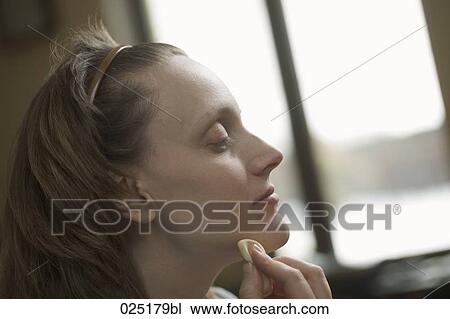 Stock Image - portrait of young woman applying make-up. Fotosearch