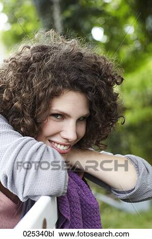 Stock Image - portrait of young woman sitting in garden. Fotosearch