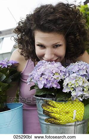 Stock Image - portrait of young woman smelling flowers. Fotosearch