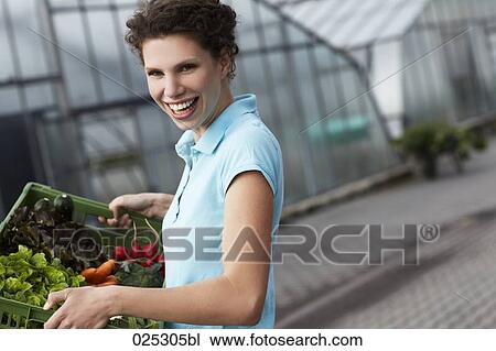 Stock Image - portrait of young woman with basket full of vegetables. Fotosearch