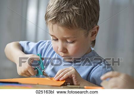 young boy cutting paper with scissors View Large Photo Image Stock Image - young boy cutting paper with scissors. Fotosearch