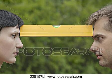 young woman and man face to face balancing spirit-level View Large Photo Image Stock Image - young woman and man face to face balancing spirit-level. Fotosearch